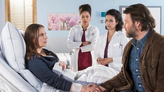 Bild: ARD/Jens Ulrich Koch Vivienne Kling (Jane Chirwa) und Dr. Leyla Sherbaz (Sanam Afrashteh) haben schlechte Nachrichten für Gesine (Julia Jäger) und deren Mann Frank (Christian Rudolf). Gesines Fuß wird nicht mehr ausreichend durchblutet.