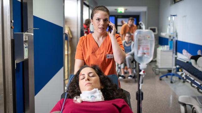Bild: ARD/Felix Abraham Maxi Bloch (Leonie Rainer) bekommt in der Notaufnahme eine Wachkomapatientin (Damineh Hojat, liegend), die bei einem Krankentransport in ein anderes Pflegeheim verunfallt ist und ruft Louisa Neukamm zur Hilfe.