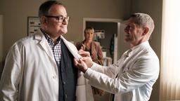 Hans-Peter Brenners (Michael Trischan, li.) ehemalige Prüferin Dr. Sylvia Jessel (Esther Esche, mi.) betritt gerade das Ärztezimmer, als Dr. Rolf Kaminski (Udo Schenk, re.) dem frischgebackenen Doktor das neue Namensschild anheftet.