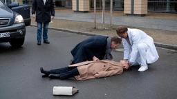 Martin Stein (Bernhard Bettermann, re.) und Kai Hoffmann (Julian Weigend, 2.v.li.) sind in einem Streit aneinander geraten. Maria Weber (Annett Renneberg, liegend) wollte zu ihnen eilen und hat dabei ein Auto übersehen. Der Autofahrer (Komparse, li.) konnte nicht mehr schnell genug bremsen.
