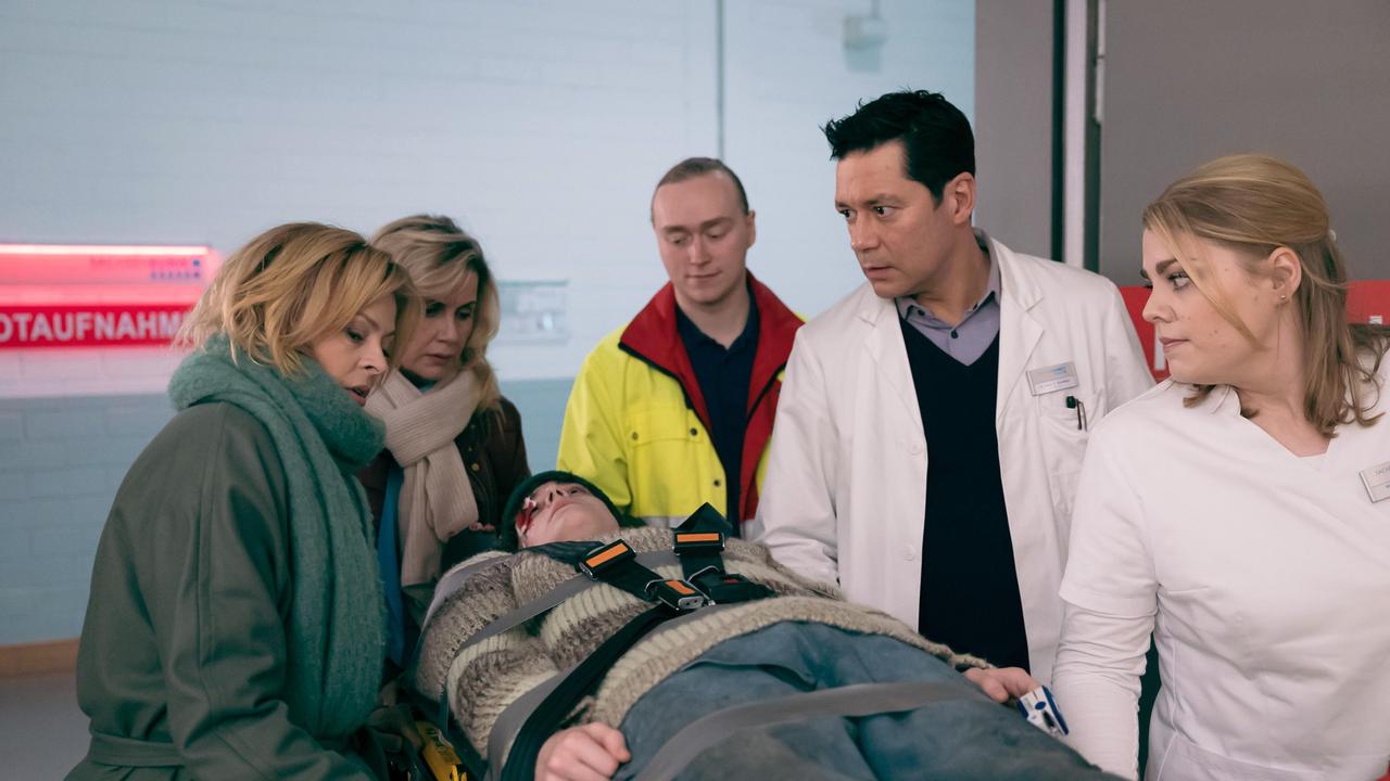 Sarah Marquardt (Alexa Maria Surholt, 2.v.li.) und Dr. Ina Schulte (Isabell Gerschke, li.) ist auf dem Weg zu einer Tagung ein junger Mann (Claude Albert Heinrich, liegend) vors Auto gelaufen. In der Sachsenklinik werden sie von Dr. Philipp Brentano (Thomas Koch, 2.v.re.) und Schwester Miriam (Christina Petersen, re.) entgegengenommen.