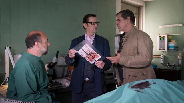 Bild: ARD/Sandra Hoever Dr. Strahl (Christoph Tomanek) findet bei der toten Seniorin einen Zettel. Der Inhalt des Schreibens veranlasst Lars (Ingo Naujoks) und Finn (Sven Martinek), den Tatort noch einmal genauer zu untersuchen.