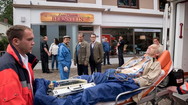 Bild: ARD/Georges Pauly Ein brutaler Überfall auf ein Bernstein-Schmuckgeschäft in Scharbeutz: Weil der Bernsteinschleifer Enno Claasen (Hans-Heinrich Hardt ) ungeplant früher vom Strand zurückkommt, überrascht er zwei Einbrecher auf frischer Tat und wird dabei von einem Schuss lebensgefährlich verletzt. Finn Kiesewetter (Sven Martinek), Lars Englen (Ingo Naujoks, 2.v.r. mit Komparsen h.) Dr. Henning Strahl (Christoph Tomanek, 4.v.r. mit Komparsen) ermitteln.