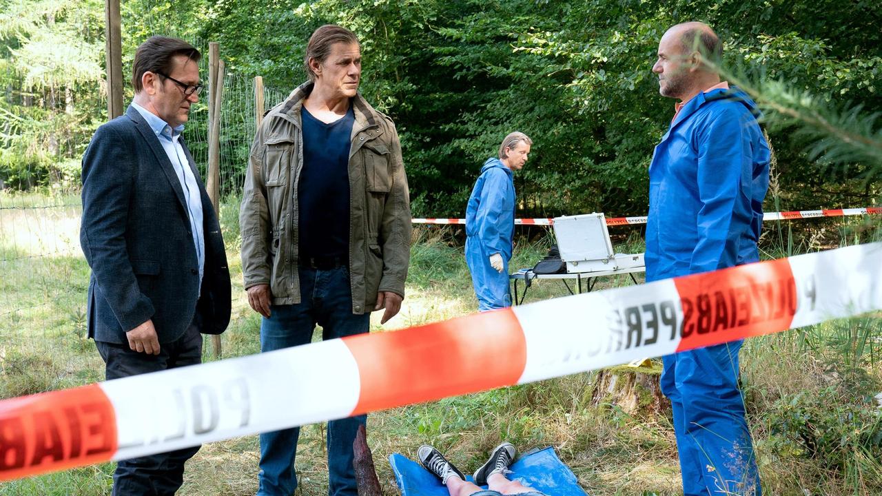Lars (Ingo Naujoks) und Finn (Sven Martinek) begutachten den Tatort,  Strahl (Christoph Tomanek, r. mit Komparse, h.) vermutet, dass Mia Kalisch (Antonia Breidenbach) bei einem Kampf auf eine Astspitze gestürzt ist.