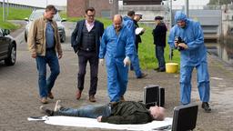 Lothar Klump (liegend, Komparse) ist ertrunken. Dr. Strahl (Christoph Tomanek) weist Finn (Sven Martinek) und Lars (Ingo Naujoks) auf Brandwunden hin.