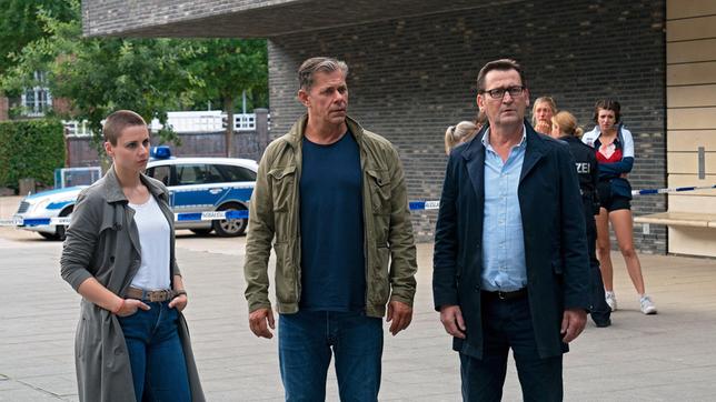 Bild: ARD/Marion von der Mehden Nina (Julia E. Lenska), Finn (Sven Martinek) und Lars (Ingo Naujoks, r. mit Kompars:innen) ermitteln am Turnverein.