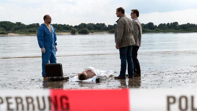 Bild: ARD/Georges Pauly Pathologe Dr. Strahl (Christoph Tomanek), Lars Englen (Ingo Naujoks) und Finn Kiesewetter (Sven Martinek) haben es mit einer Leiche am idyllischen Ostseestrand zu tun. Es handelt sich um den leblosen Körper des jungen Alexander Blohm (Daniel Axt).