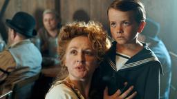 Colina Kandl (Brigitte Hobmeier) umarmt ihren Sohn Max (Josef Staber), mit dem ihr Ehemann Rupp plötzlich auf dem Oktoberfest auftaucht. Motiv aus Folge 5 "Aufbruch in ein neues Jahrhundert"
