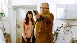 Daniela (Alice Gruia) sucht Schutz hinter Klaus (Hartmut Volle), der mit gezogener Waffe, den Entführern entgegentritt.