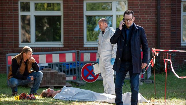 Bild: ARD/Thorsten Jander Der Krankenhausclown Fidan Petrov (Philipp Boos, liegend) liegt erschlagen im Hinterhof der Klinik. Die Kommissare Finn Kiesewetter (Sven Martinek) und Lars Engel (Ingo Naujoks, r. mit Christoph Tomanek) ) finden heraus, dass der Tote ein Betrüger war.