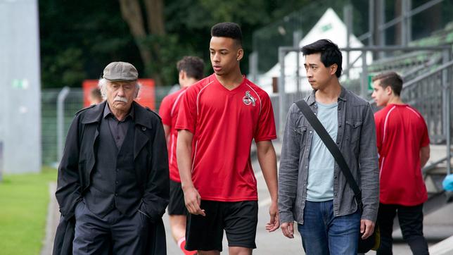 Edwin Bremer (Tilo Prückner) und Hui Ko (Aaron Le) befragen den FC-Köln-Fußballer Timo (Emmanuel Kämpfer) nach seinen verletzten Kollegen.