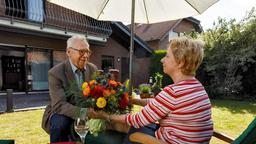 Günter Hoffmann (Peter Lerchbaumer) bringt seiner Frau Heidrun (Verena Plangger) Blumen.