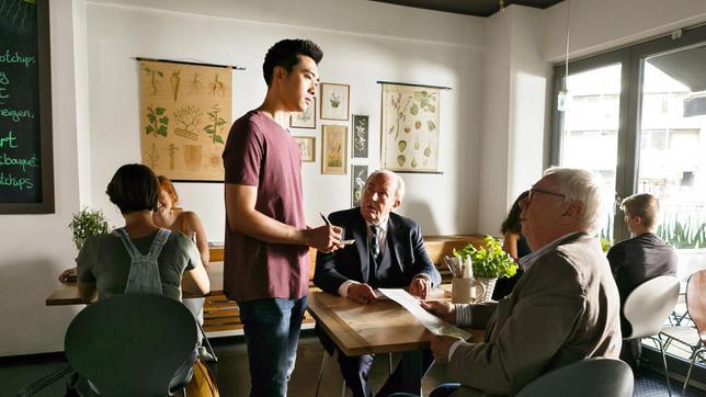 Hui (Aaron Le, r. mit Komparsen) arbeitet undercover im Restaurant. Er nimmt die Bestellungen von Günther (Peter Lerchbäumer) und Plocher (Michael Prelle) entgegen.