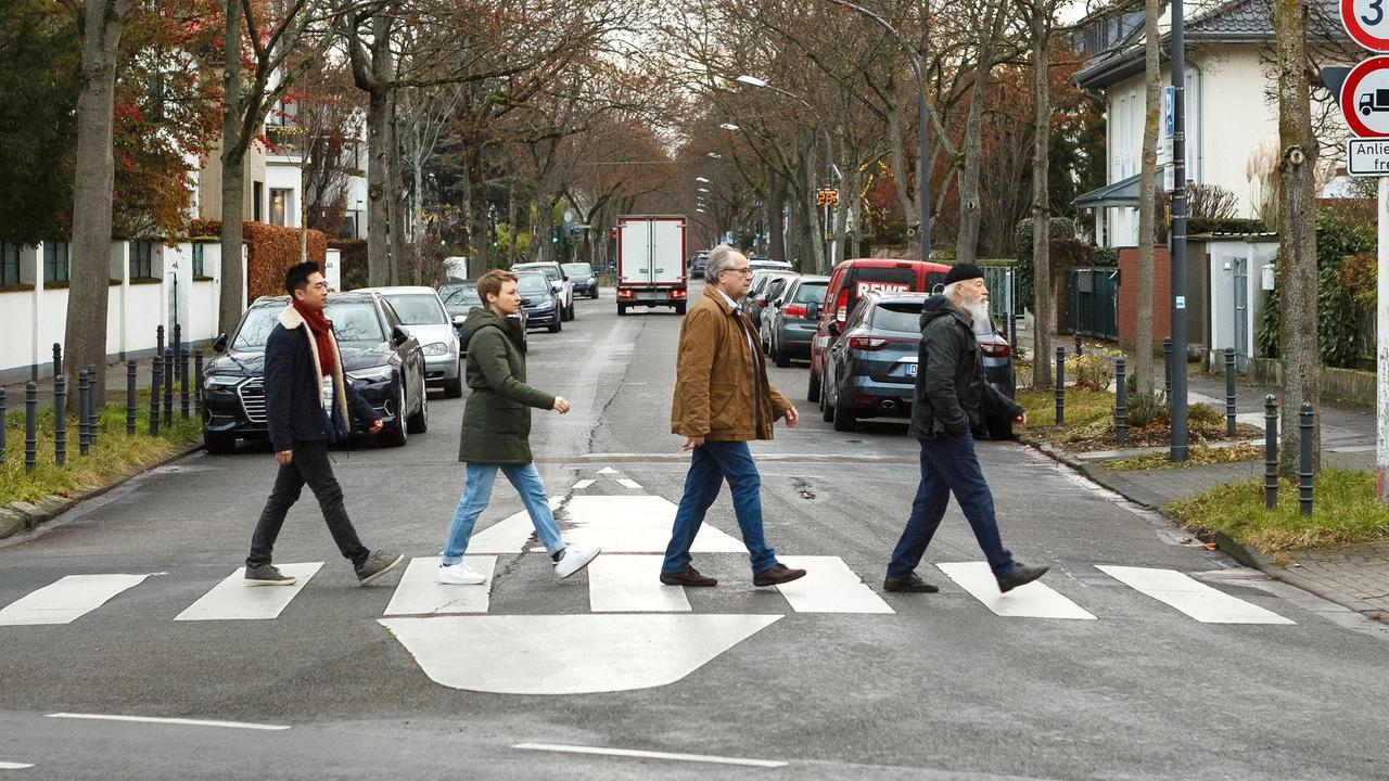 Hui Ko (Aaron Le), Vicky Adam (Katja Danowski), Klaus Schmitz (Hartmut Volle) und Reinhard Bielefelder (Bill Mockridge) überqueren den Zebrasteifen wie die "Beatles".