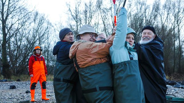 Bild: ARD/Kai Schulz Vicky Adam (Katja Danowski), Reinhard Bielefelder (Bill Mockridge), Klaus Schmitz (Hartmut Volle) und Hui Ko (Aaron Le) sind im Rahmen einer Teambildungsmaßnahme beim Angeln. Gemeinsam versuchen sie etwas Schweres aus dem Wasser zu ziehen (mit Komparse).