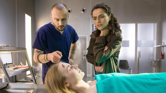 Dr. Jan Conrad (Juri Padel) zeigt Jasmin Sayed (Sesede Terziyan) die Platzwunde am Kopf der Toten. Doch die war nicht todesursächlich. Was ist am Tatort passiert?
