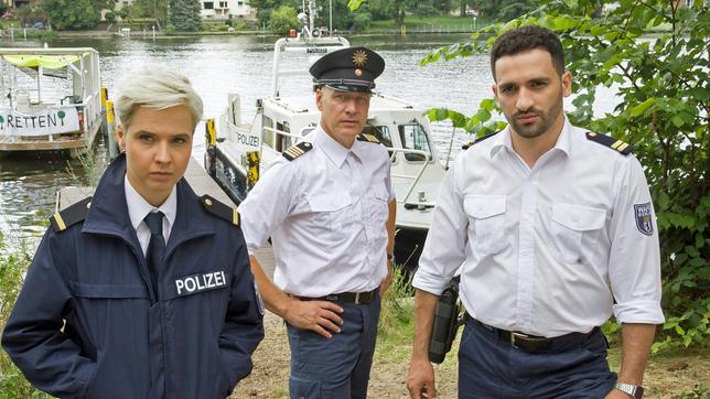 Bild: ARD/Daniela Incoronato Skeptisch verfolgen Marlene Weber (Oska Melina Borcherding), Wolf Malletzke (Christoph Grunert) und Fahri Celik (Hassan Akkouch) die Aussagen der Umweltaktivist:Innen im Camp an der Havel.