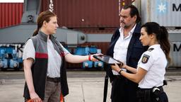 Arda (Yasemin Cetinkaya) und Jäger (Markus John) gehen durch gestapelte Container und treffen auf Karin Uhr (Katharina Abel).