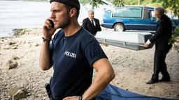 Frank van Dijk (Niklas Osterloh) telefoniert, währen die Leiche abtransportiert wird (mit Komparsen).