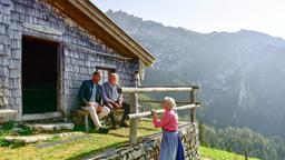 Jerry Paulsen (Peter Marton, l.) sitzt mit Josef Lahner (Franz Buchrieser, r.) vor dessen Hütte auf der Bank - der vertraut ihm ein dunkles Geheimnis an. Die alte Wirtin Paula (Luise Deschauer, unten) steht vor ihnen am Zaun.