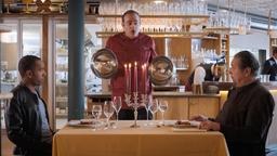 Beissl (Andreas Giebel) und Jerry (Peter Marton) werden im Restaurant "nouvelle cuisine" von Michelle Perrin (Miguel Abrantes Ostrowski) persönlich bedient.