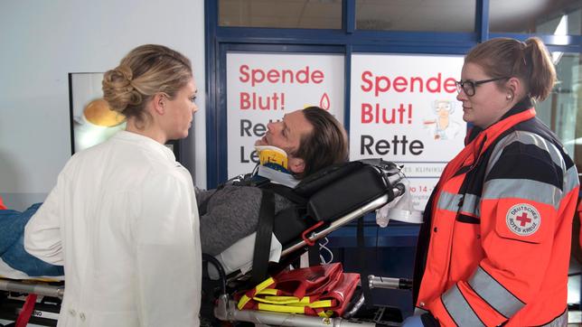 Britta (Jelena Mitschke) trifft Peer (Jörg Pintsch, M. mit Komparsin) in der Notaufnahme und erfährt, dass Sigrid bei dem Unfall schwer verletzt wurde.