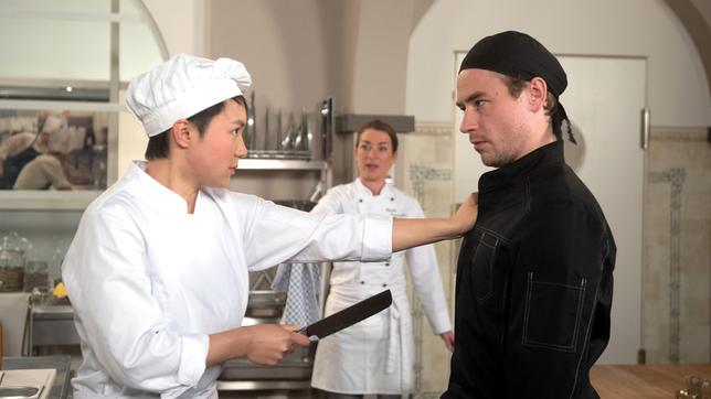 Carla (Maria Fuchs) bekommt entsetzt mit, wie Ellen (Yun Huang) Oliver (Niklas Löffler) mit einem Messer bedroht.