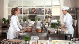 Carla (Maria Fuchs) hält mit Ellas (Yun Huang) Hilfe, die Stellung in der Küche, nachdem Gregor (Wolfram Grandezka) ihren Mitarbeitern gekündigt hat.