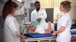 Hendrik (Jerry Kwarteng) kümmert sich um Thomas (Gerry Hungbauer), der nach einer Medikamentengabe durch Sara (Antonia Jungwirth) zusammengebrochen ist (mit Kira Bulz).