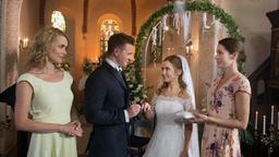 Hochzeit: Moritz (Felix Jordan) und Eteri (Marija Mauer) stecken sich vor den Trauzeuginnen Eva (Andrea Lüdke) und Eliane (Samantha Viana.), sowie den Hochzeitsgästen, die Ringe an.
