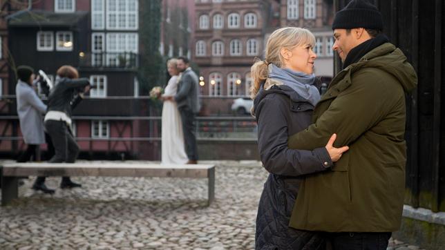 Katrin (Nicole Ernst) und Leo (Daniel Hartwig) stellen lachend fest, dass sie keine Hochzeit brauchen um miteinander glücklich zu sein (mit Kompas:innen).