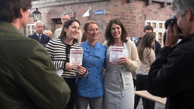 Bild: ARD/Nicole Manthey Zu Torbens (Joachim Kretzer, h.) und Thomas' (Gerry Hungbauer, h.) Ärger können sich die Protestlerinnen Carla (Maria Fuchs), Eliane (Samantha Viana, 2.v.l. mit Komparse) und Helen (Patricia Schäfer) über reges Interesse der Presse freuen.