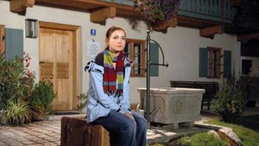 Bild: ARD/Jo Bischoff Laura sitzt auf einem Koffer und wartet