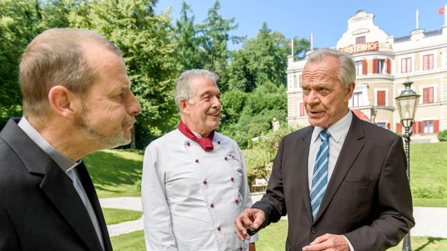 Bild: ARD/Christof Arnold André (Joachim Lätsch) amüsiert sich über Werners (Dirk Galuba) vergebliche Versuche, Pfarrer Rimpel (Christian Buse) umzustimmen.