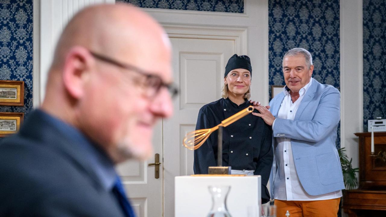 André (Joachim Lätsch) rührt vor der Jury (Komparse) die Werbetrommel für Leentje (Antje Mairich).