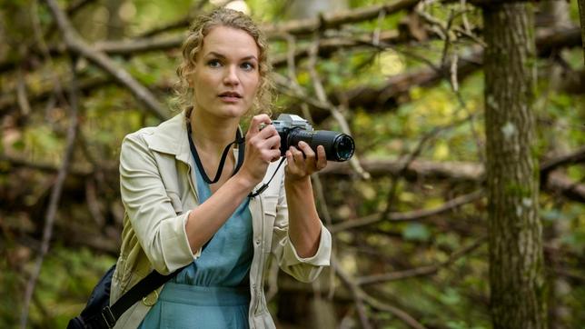 Beim Fotografieren im Wald bemerkt Maja (Christina Arends) erschrocken, dass jemand mit einem Gewehr auf ein Reh zielt.