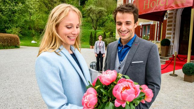 Clara (Jeannine Wacker) muss enttäuscht mit ansehen, wie Adrian (Max Alberti) Desirée (Louisa von Spies) Blumen schenkt.