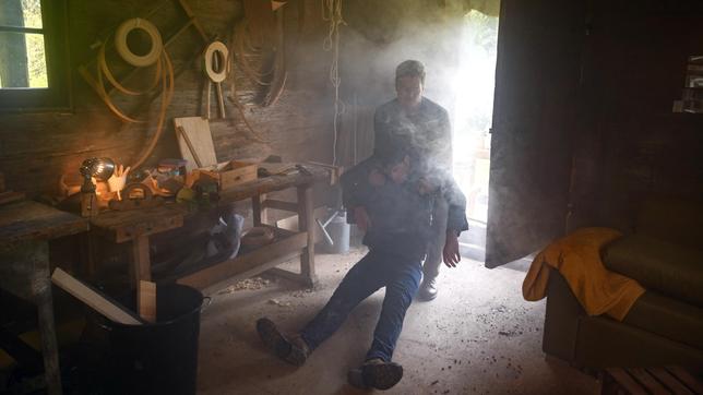 Henry (Patrick Dollmann, h.) zieht den leblosen Joshua (Julian Schneider) aus der brennenden Werkstatt.