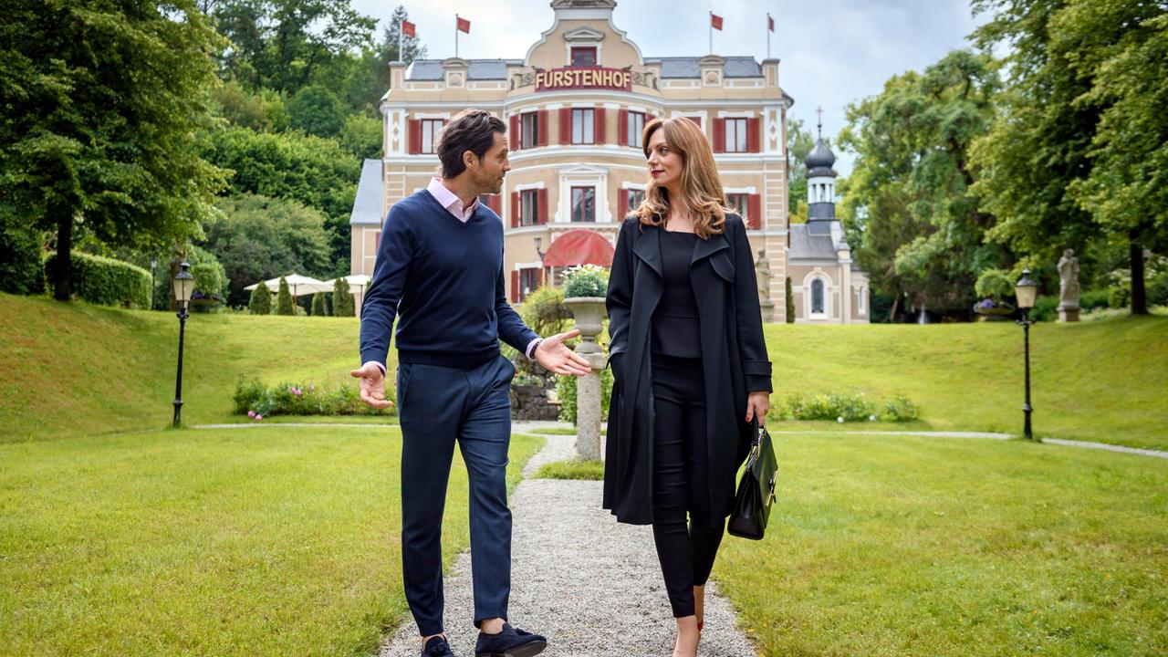 Im Park des Fürstenhof: Ariane (Viola Wedekind) äußert vor Karl (Stephan Käfer) ihre Sorge, dass Roberts Aktionismus ihren Plan verzögert.
