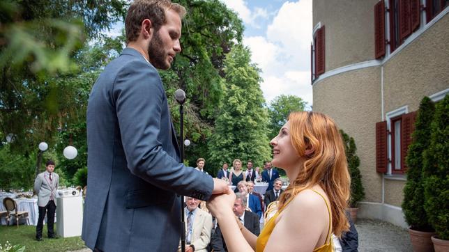 Bild: ARD/Christof Arnold Maja (Christina Arends, h.) beobachtet, wie Constanze (Sophia Schiller) Florian (Arne Löber) spontan einen Heiratsantrag macht (mit Komparsen).