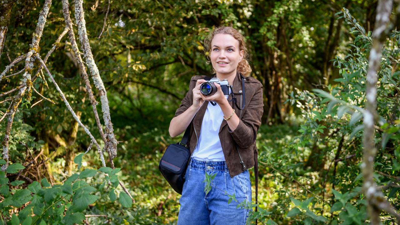 Maja (Christina Arends) genießt es im Bannwald fotografieren zu dürfen - und bemerkt dabei nicht, dass sie den Deckel eines Filmdöschens verliert ...