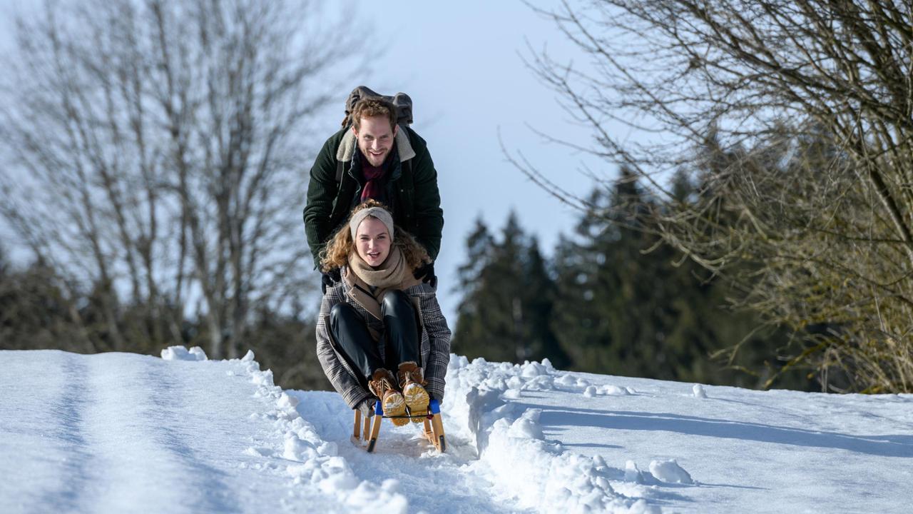 Maja (Christina Arends) und Florian (Arne Löber) machen auf ihrem Heimweg von der Almhütte eine Schlittenfahrt.