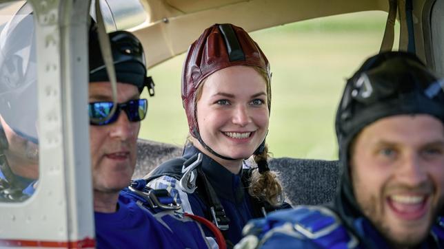 Maja (Christina Arends) und Florian (Arne Löber) sind voller Vorfreude auf ihren Fallschirmsprung (mit Komparse).
