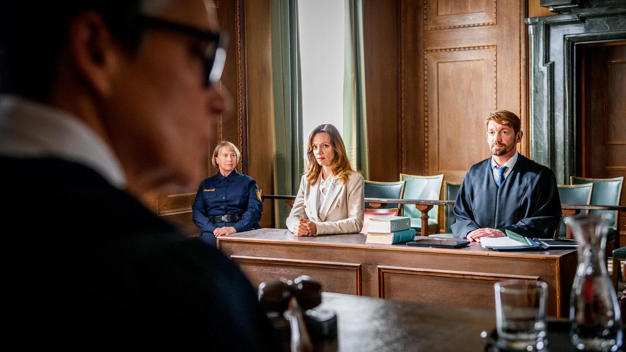 Mit ihrem Anwalt (Matthias Saffert) als Beistand, wird Ariane (Viola Wedekind) von Richterin Bamminger (Claudia-Sofie Jelinek, vorne) der Prozess gemacht (mit Komparsin).
