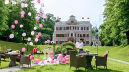 Vanessa (Jeannine Gaspár) beobachtet amüsiert, wie Robert (Lorenzo Patané) mit vollem Körpereinsatz versucht, die Ballons am Wegfliegen zu hindern.