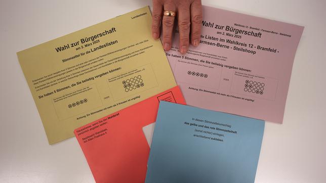 Bild: picture alliance/dpa | Marcus Brandt Ein Wahlhelfer legt Stimmzettel und Umschläge für einen Pressetermin auf einen Tisch in der zentralen Briefwahlstelle zur Bürgerschaftswahl und Bundestagswahl 2025 auf dem Gerhart-Hauptmann-Platz.