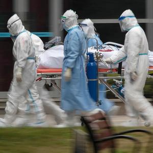 Menschen in Schutzkleidung transportieren einen Patienten