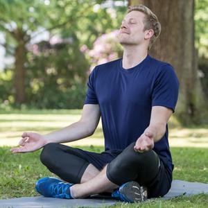 Ein junger Mann macht Yoga im Park