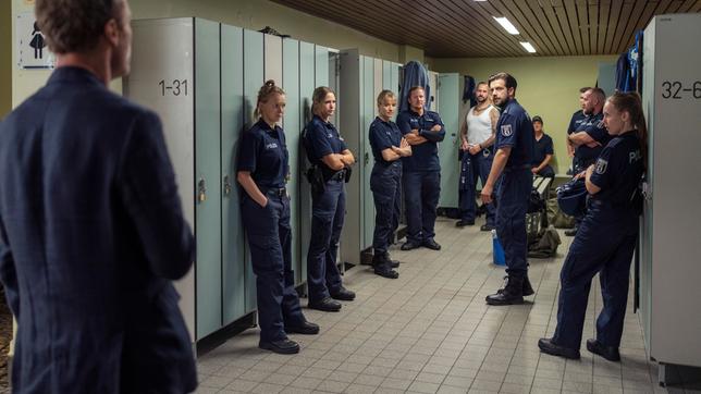 Bild: rbb/Marcus Glahn Kommissar Karow (Mark Waschke, links) verhört Gruppenführer Guido Konrad (Christoph Jöde, Mitte). Unter den KollegInnen ist auch Tina Gebhardt (Bea Brocks, 3.v.l.).