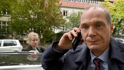 Peter Michael Schnabel (Martin Brambach) telefoniert an seinen Dienstwagen gelehnt, auf der anderen Seite Leo Winkler (Cornelia Gröschel)